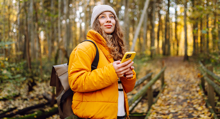 Hoe sterk is jouw weerstand? Persoon wandelt in een herfstbos en gebruikt een smartphone